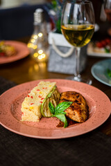 Delicious chicken steak with rice and vegetables with a glass of wine on the table