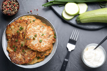 Delicious zucchini fritters served on grey table, flat lay