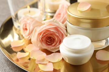 Fototapeta na wymiar Composition with skin care products and roses on golden tray, closeup