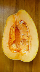 A large pumpkin carved in the middle on a wooden table. On the subject of fruits and vegetables.