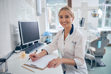 Happy female dentist working in modern office