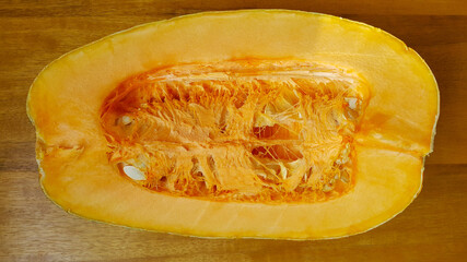 A large pumpkin carved in the middle on a wooden table. On the subject of fruits and vegetables.