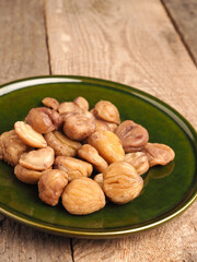 Organic chestnuts on a rustic green plate, healthy or seasonal food concept