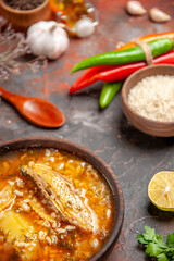 bottom view bowl of chicken soup wood spoon hot peppers bowls of black pepper rice slice of lemon on isolated background