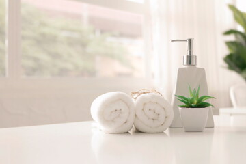 Soap dispenser and spa towel ,Roll up of white towels on white table with copy space,towels studio shot on white table