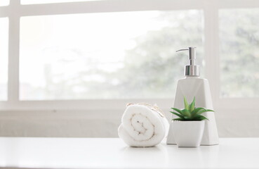 Obraz na płótnie Canvas Soap dispenser and spa towel ,Roll up of white towels on white table with copy space,towels studio shot on white table