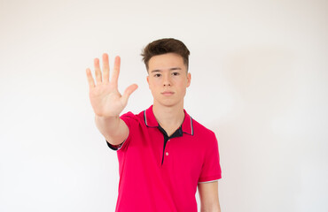 Teen boy doing stop sign with palm of hands, on white background. Beautiful caucasian teenager making stop gesture.