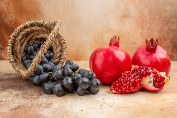 front view fresh black grapes with pomegranates on light background photo tree ripe fruits mellow vitamine