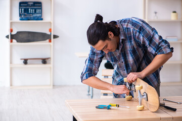 Young man repairing skateboard at workshop