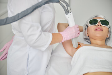 Naklejka premium Doctor directing the laser beam on the patient underarm area