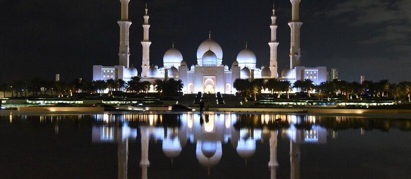 Spiegelung der n&auml;chtlich beleuchteten Scheich-Zayid-Moschee auf blanker Wasseroberfl&auml;che