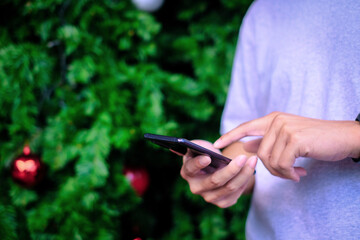 Man holding smartphone with christmas tree background, Technology concept.