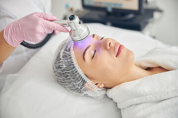 Doctor using a photo beauty device in cosmetology