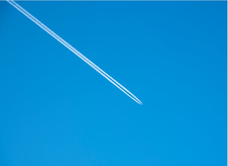 The white trail of the plane in the bright blue sky.