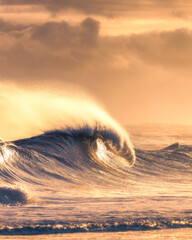 Rough surf and large waves with spray being lit up with golden sunlight. Long Island New York