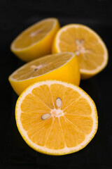 Fresh lemons cut in half on a black background.
Close-up.