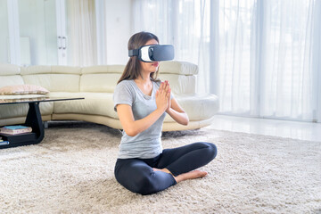 Woman doing yoga exercise with VR glasses at home