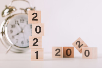 wood wooden cubes with the New year 2021 and goal icon. New year target plan with wood blocks cubes on wooden and clock table
