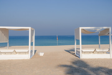 Relaxing empty beach with sun bed, sea landscape. Summer vacation travel holiday concept.