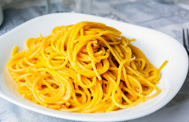 Large portion of spaghetti carbonara in a white dish.