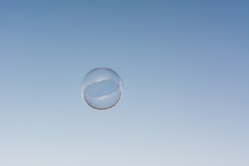 A soap bubble flying in the blue and clean sky