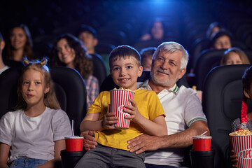 Grandfather with grandson on knees in cinema.