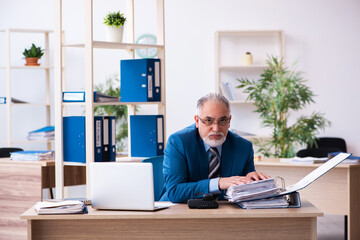 Old male bookkeeper unhappy with excessive work at workplace