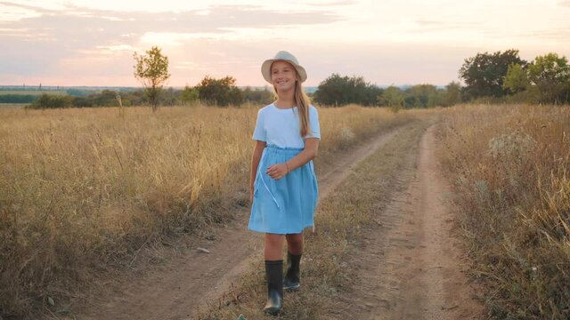Pretty girl in blue dress walks in a field.