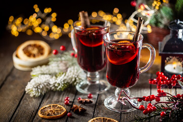 christmas hot mulled wine with spices and fruits on wooden background with christmas lights