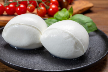 Fototapeta na wymiar Cheese collection, white balls of soft Italian cheese mozzarella, served with red cherry tomatoes, fresh basil leaves