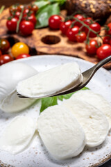 Cheese collection, eating. of white soft Italian cheese mozzarella, served with red cherry tomatoes, fresh basil leaves