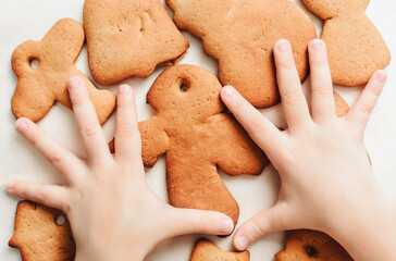 Childs hands on gingerbread cookie. The tradition of making gingerbread cookies for New Year and Christmas.