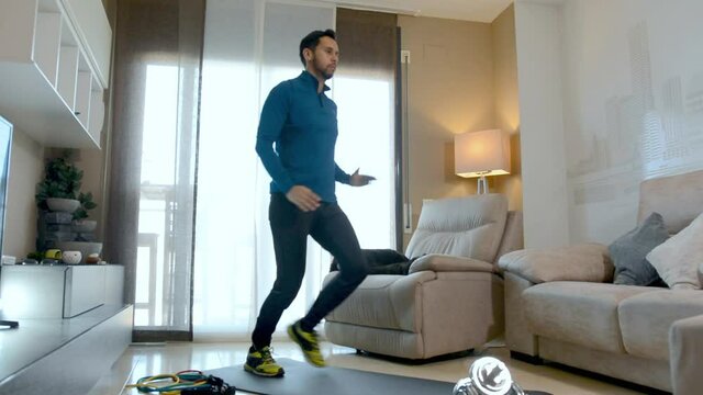 Latin man, doing a workout in his living room, does sit-ups, stretches and squats