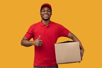 Black delivery man holding cardboard box showing thumb up
