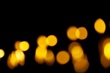 Yellow bokeh lights on a black background. Abstract shiny pattern in defocus.
