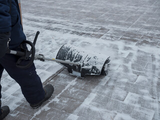 Worker clears the sidewalk of snow. Mechanical snow blower with a brush. Concept of mechanization...