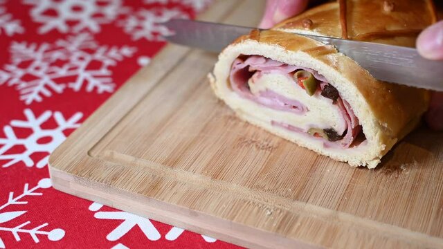 Traditional bread filled with ham, olives and raisins  for the Christmas season. Venezuelan cuisine. Cutting on a wooden board.