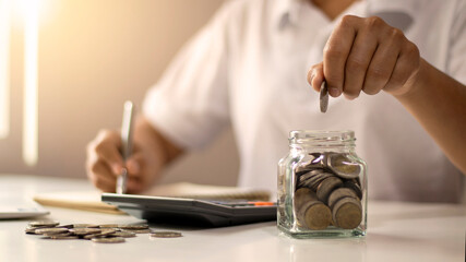 Close-up of young woman putting coin in a bottle, saving money, money saving concept for financial accounting.