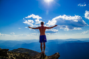 man stands on top of a mountain with open hand