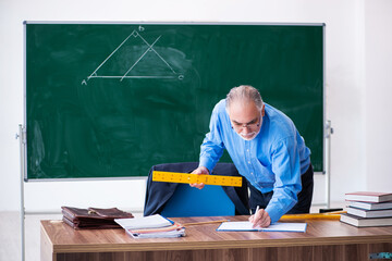 Old male geometry teacher holding triangle