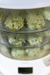 electric steamer with cooking cutlets from turkey meat and greens at home kitchen