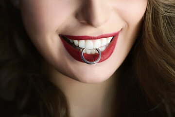 Cropped smiling bride with a perfect white smile holds a wedding ring in her white teeth