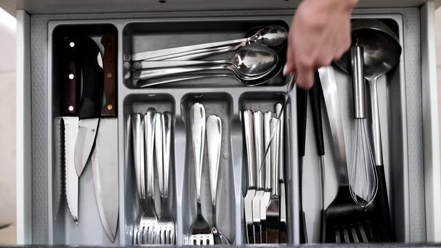 Young girl in the kitchen with a set of silver cutlery cutlery. Forks, spoons and knives. Table setting, close-up