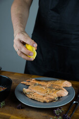Chief cook squeezes lemon on carved fish baked in salt crust. Seafood cooking. Salmon or seabass under salt crust with vegetables.