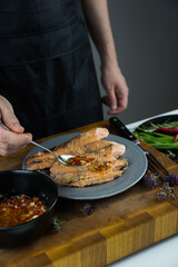 Chief cook is seasoning with chili sauce carved fish baked in salt crust. Seafood cooking. Salmon or seabass under salt crust with vegetables.