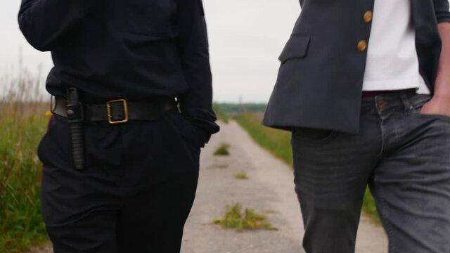 Two Russian police officers are walking along the path in the countryside.