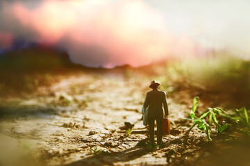 Surreal image of mysterious man walking alone in field during sunset