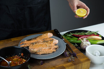 Chief cook squeezes lemon on carved fish baked in salt crust. Seafood cooking. Salmon or seabass under salt crust with vegetables.