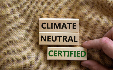 Climate neutral certified symbol. Wooden blocks with words 'Climate neutral certified'. Male hand....