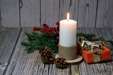 Wax candle with cones, fir branches and gifts